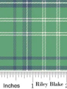 A close-up of a green plaid fabric pattern with navy and white stripes, shown with an inches ruler along the bottom edge.